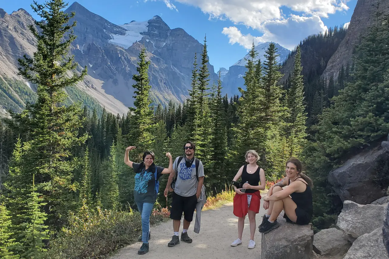 Banff Gondola - summer-tours 2 Group of hikers on a mountain trail with towering peaks and evergreens in the background.