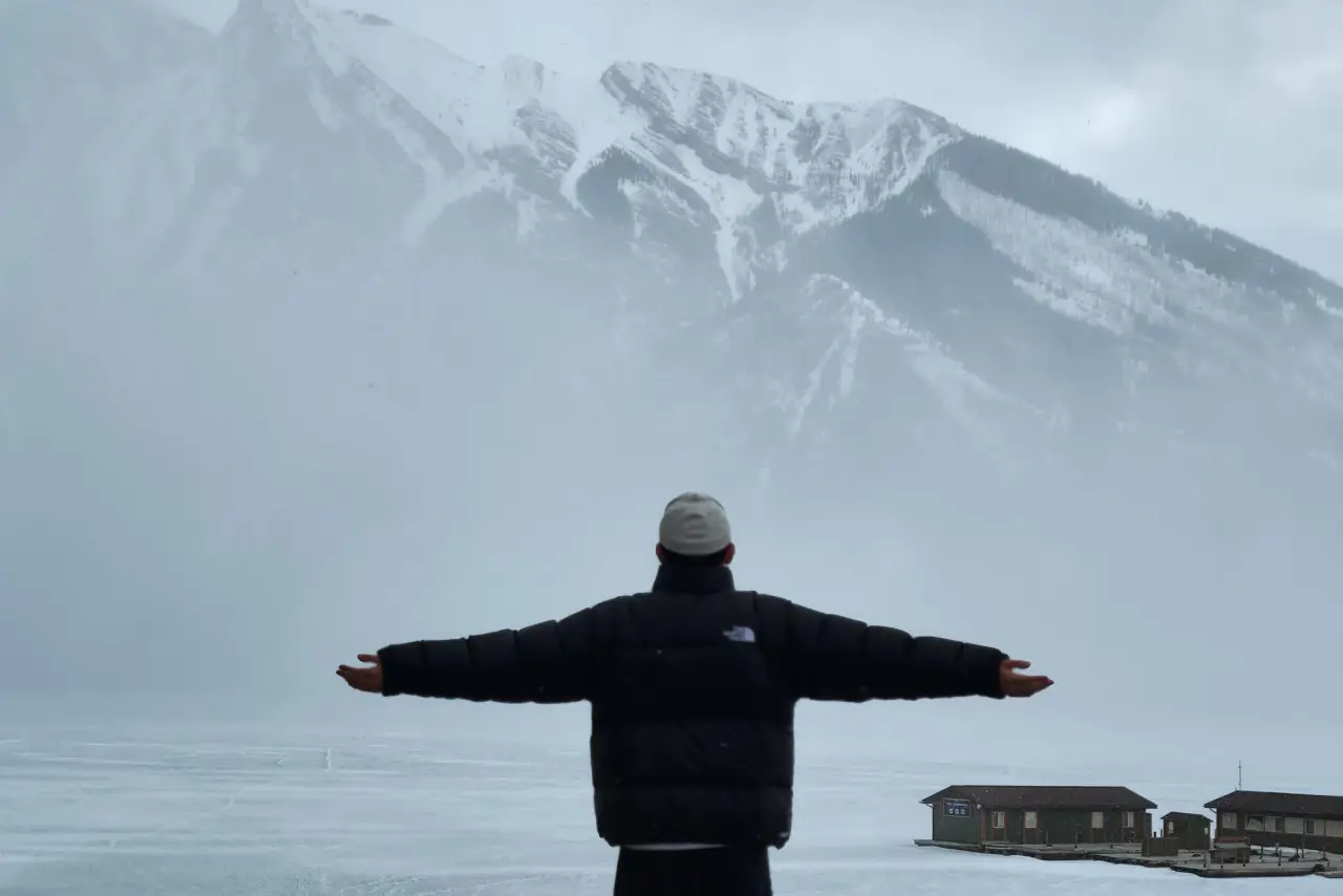 Private tours 1 Person with outstretched arms facing snowy mountains and a foggy landscape.
