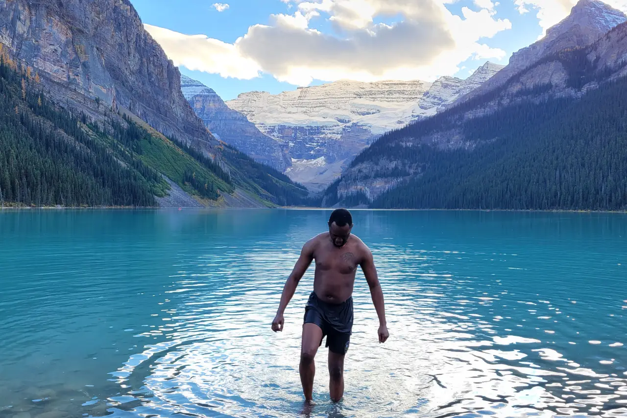 Private tours - 2(1) A person wading in a clear blue mountain lake with snowy peaks in the background.